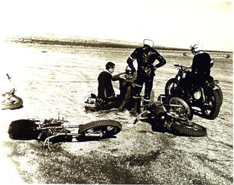 TV Tommy Ivo checks on Kenny Safford as Don Prudhomme and another rider look on after the big desert motorcycle crash. Photographer unknown